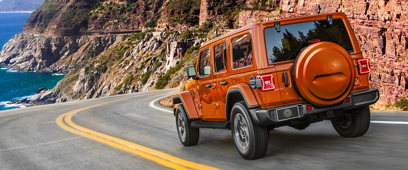 Orange jeep wrangler on winding road